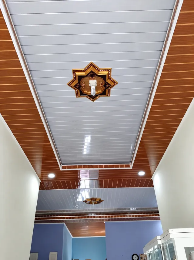 Plafon PVC putih memanjang dengan list motif kayu dan ornamen bintang di tengah
